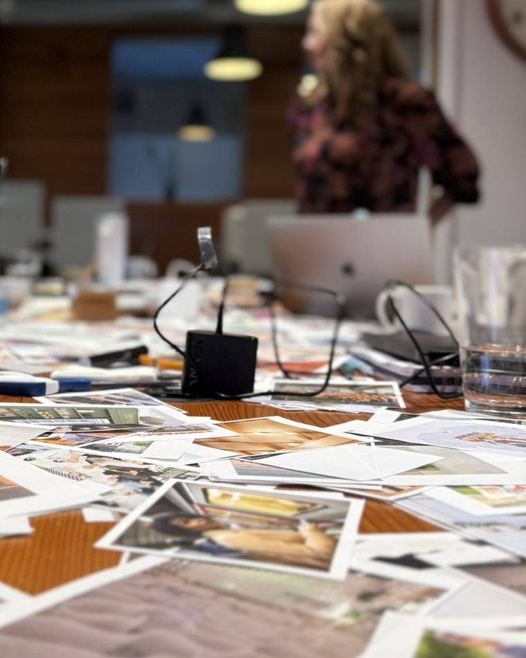 Customer research photographs spread across a workshop table during a customer experience strategy session