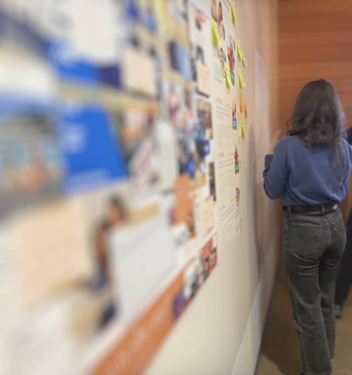 Customer journey mapping workshop: participant reviewing a wall-sized journey map of photos and sticky notes
